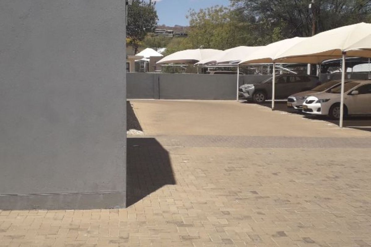 Exterior view of the office property featuring a paved parking area with covered shade-cloth parking bays.