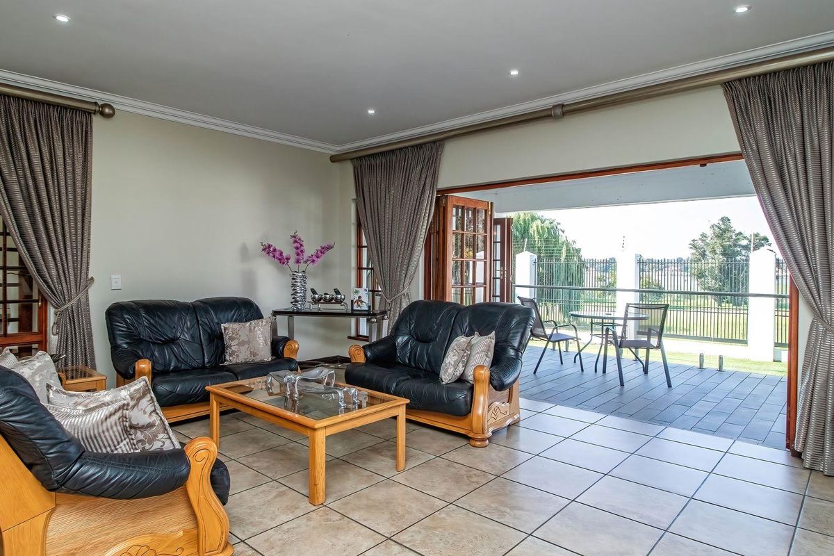 Spacious living room featuring large sliding doors that open onto a covered patio, creating a seamless indoor-outdoor flow with tiled flooring throughout.