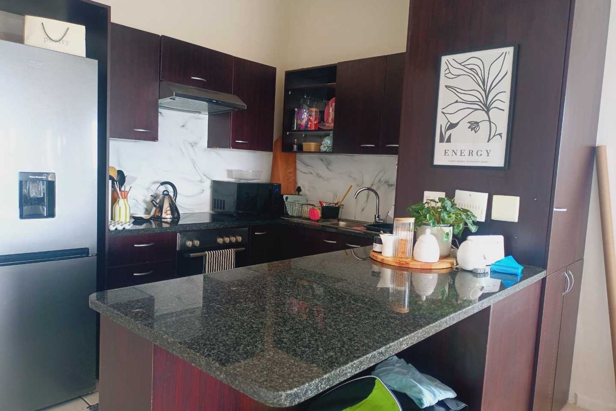 A functional kitchen featuring dark wood cabinetry, granite countertops, a marble-look backsplash, and a convenient breakfast bar for casual dining.