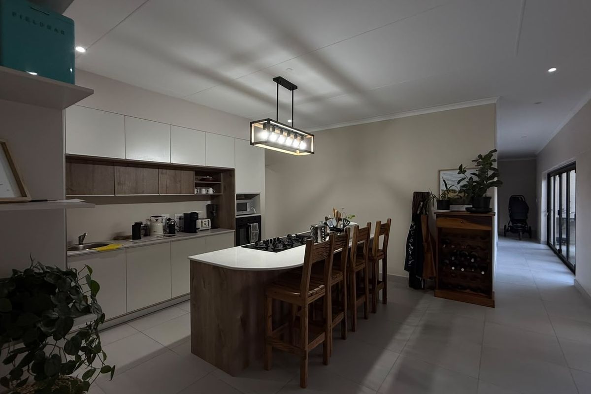 Modern open-plan kitchen featuring a central island with a gas hob, sleek cabinetry, and contemporary pendant lighting, seamlessly integrated into the living space.