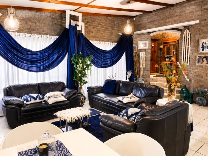 Spacious open-plan living area featuring exposed timber ceiling beams, rustic face brick walls, and neutral tiled flooring with an inviting arched entryway.