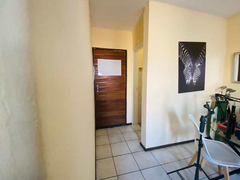 A functional hallway area featuring tiled flooring and a solid wooden door, providing access to adjacent rooms within the townhouse.