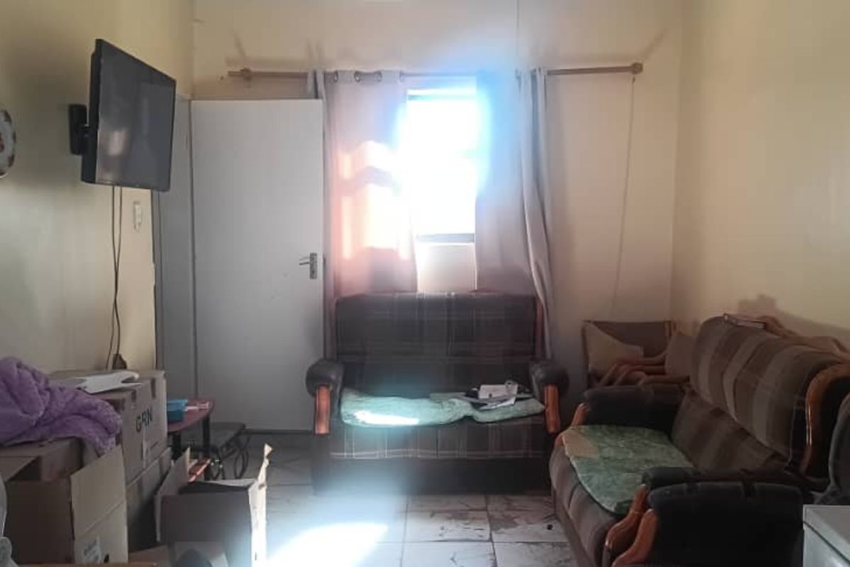 A living room space featuring tiled flooring and a window with curtains, providing a functional area for relaxation.