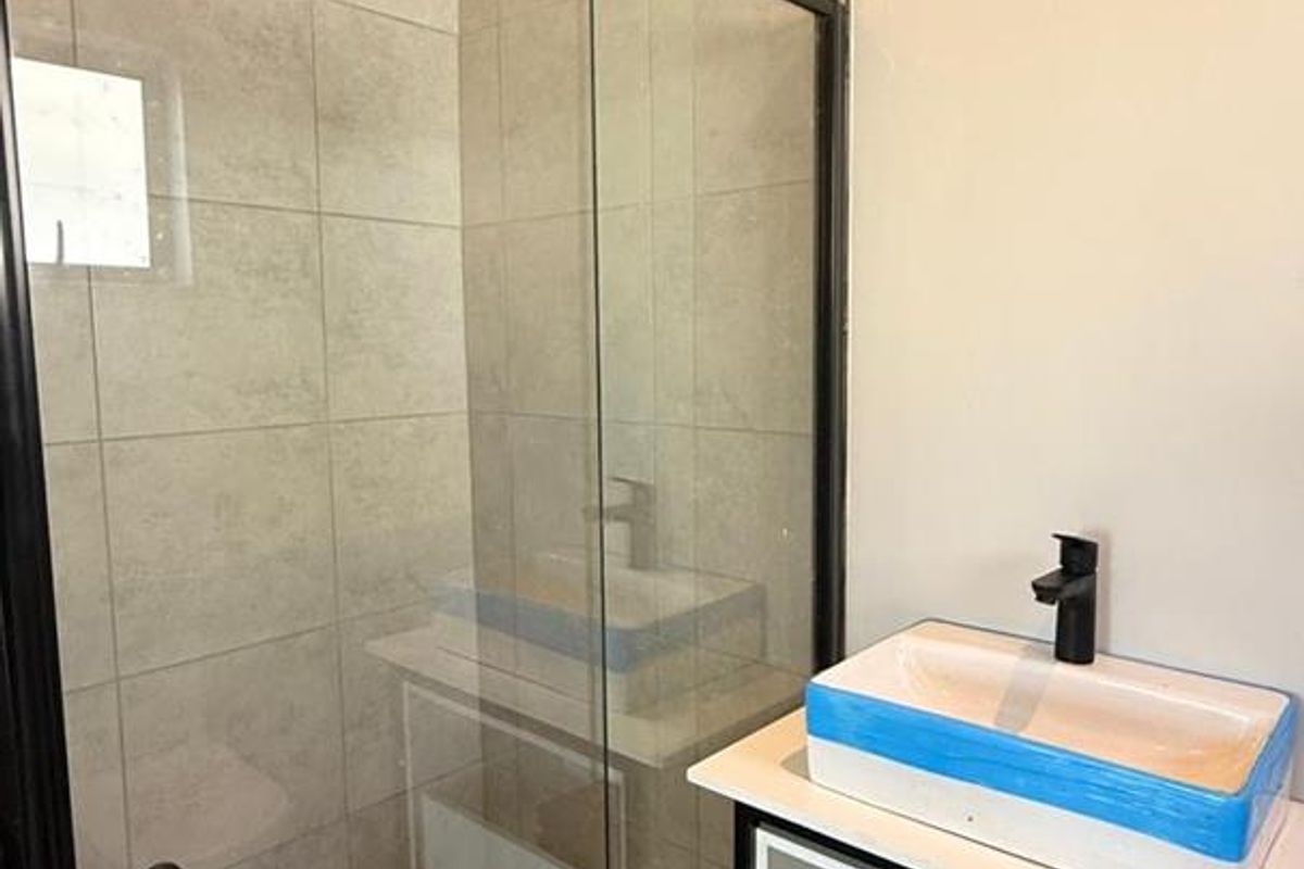 Modern bathroom featuring a walk-in shower with black frame, large format wall tiles, and a contemporary vessel sink vanity.