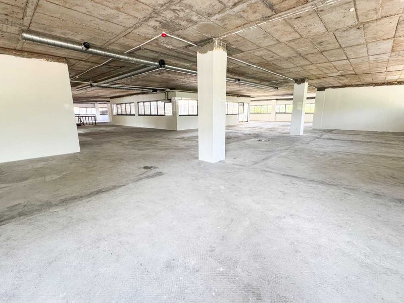 Expansive open-plan commercial space featuring industrial-style exposed concrete ceilings, ductwork, and large windows, offering a blank canvas for custom office or retail fit-outs.