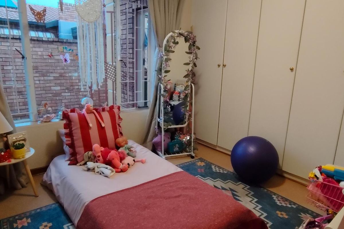 A bedroom featuring built-in cupboards and a window with security bars, providing functional storage and natural light.