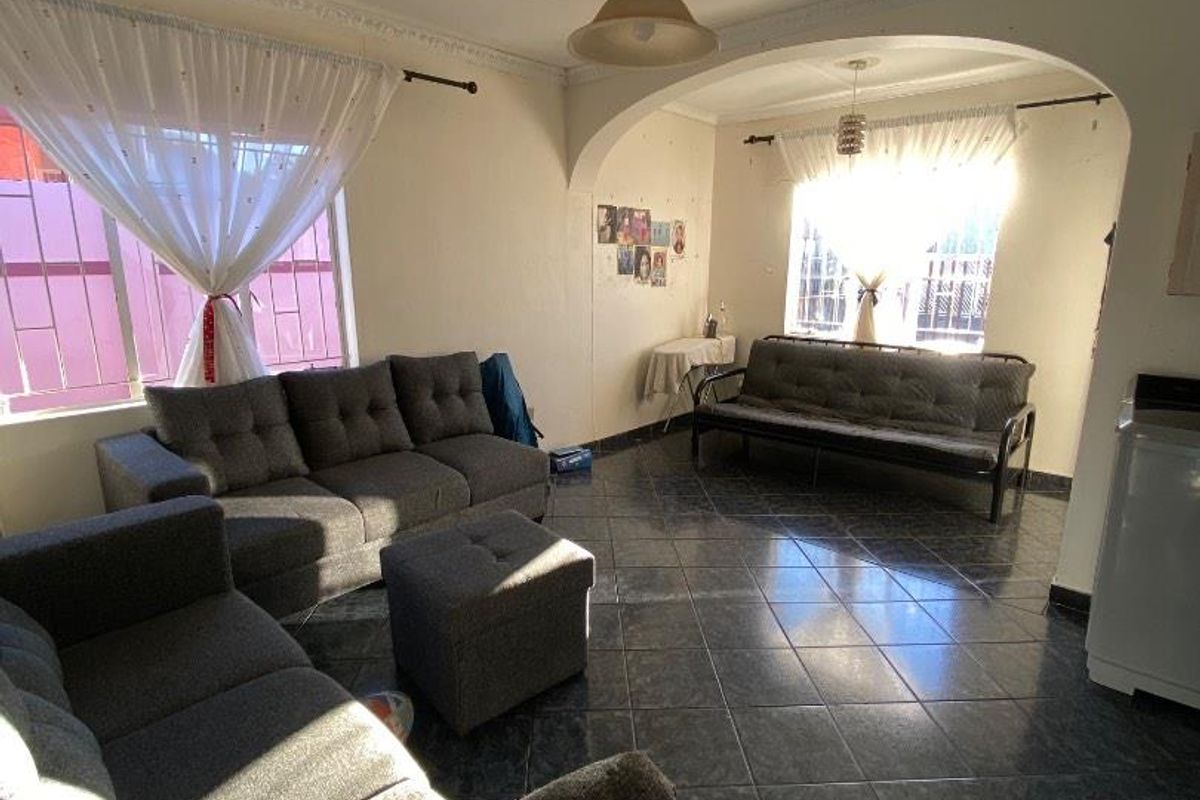 Spacious living area featuring dark ceramic floor tiles, decorative ceiling cornices, and an arched transition between living zones with ample natural light.