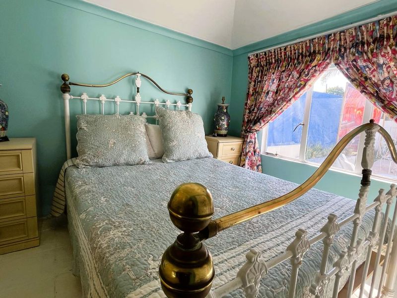 A bedroom featuring teal walls, a coved ceiling, and a casement window, providing a functional space with classic architectural details.