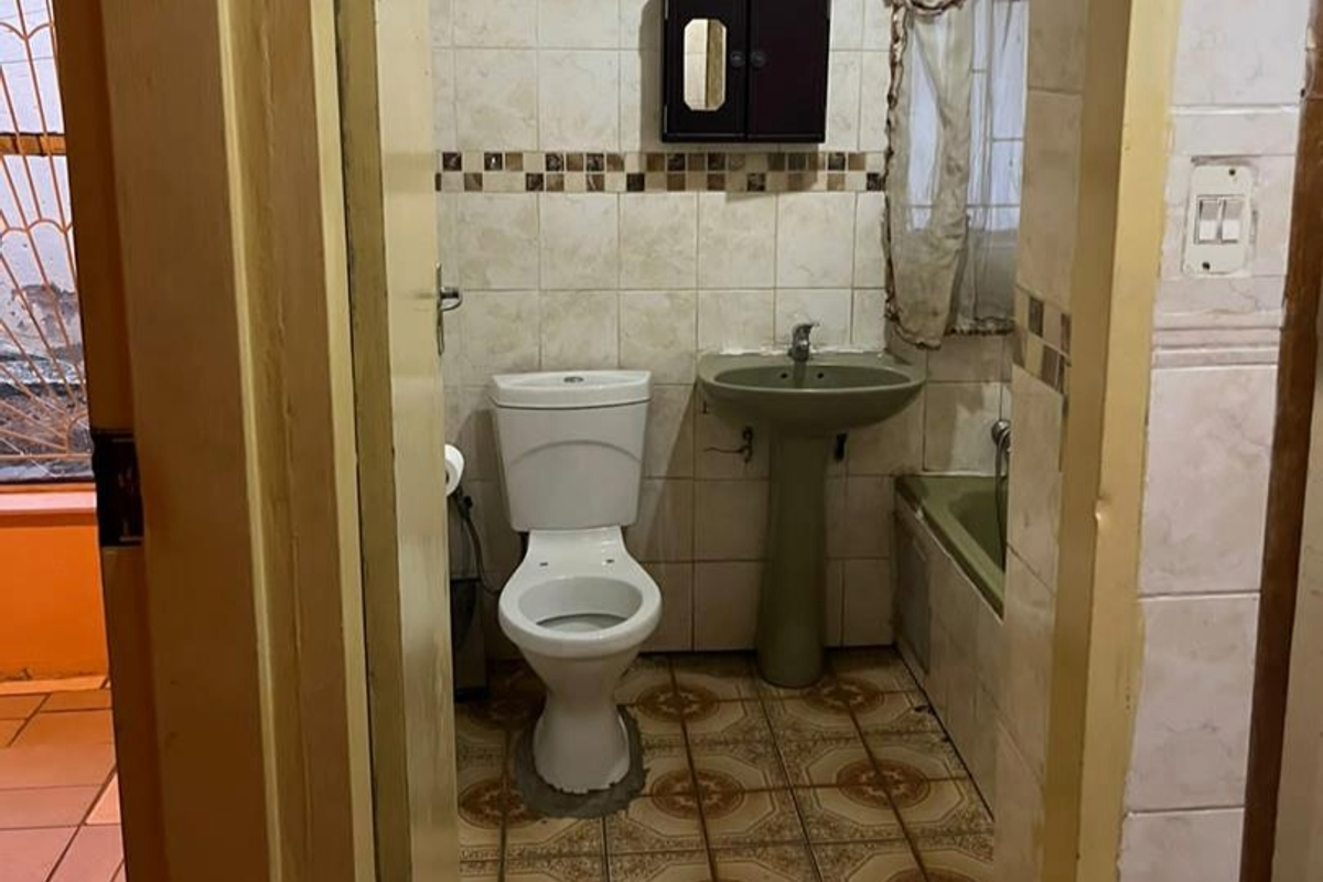 A dated bathroom featuring a pedestal basin, toilet, and bathtub with tiled walls and patterned floor tiles.