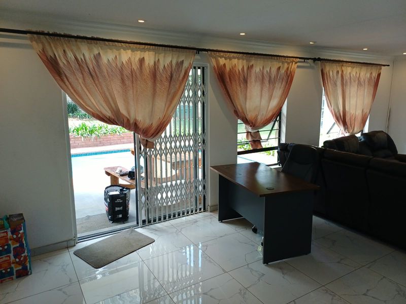 Living area featuring polished tiled flooring, recessed lighting, and a sliding glass door with a security gate providing direct access to the pool area.