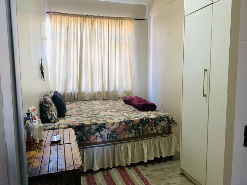 A functional bedroom featuring a built-in wardrobe and laminate flooring, offering a practical layout with natural light from the window.