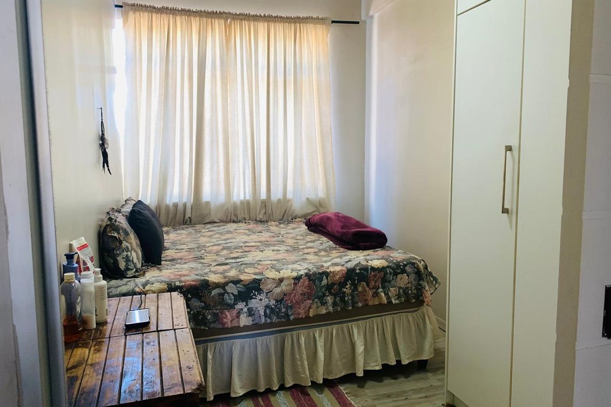 A functional bedroom featuring a built-in wardrobe and laminate flooring, offering a practical layout with natural light from the window.