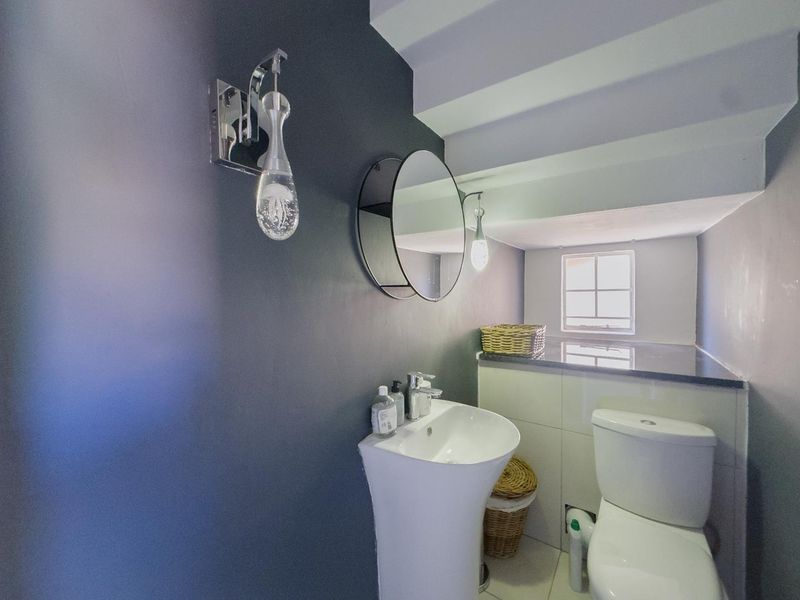 A modern guest bathroom featuring a pedestal basin, toilet, and granite countertop with stylish wall-mounted lighting.