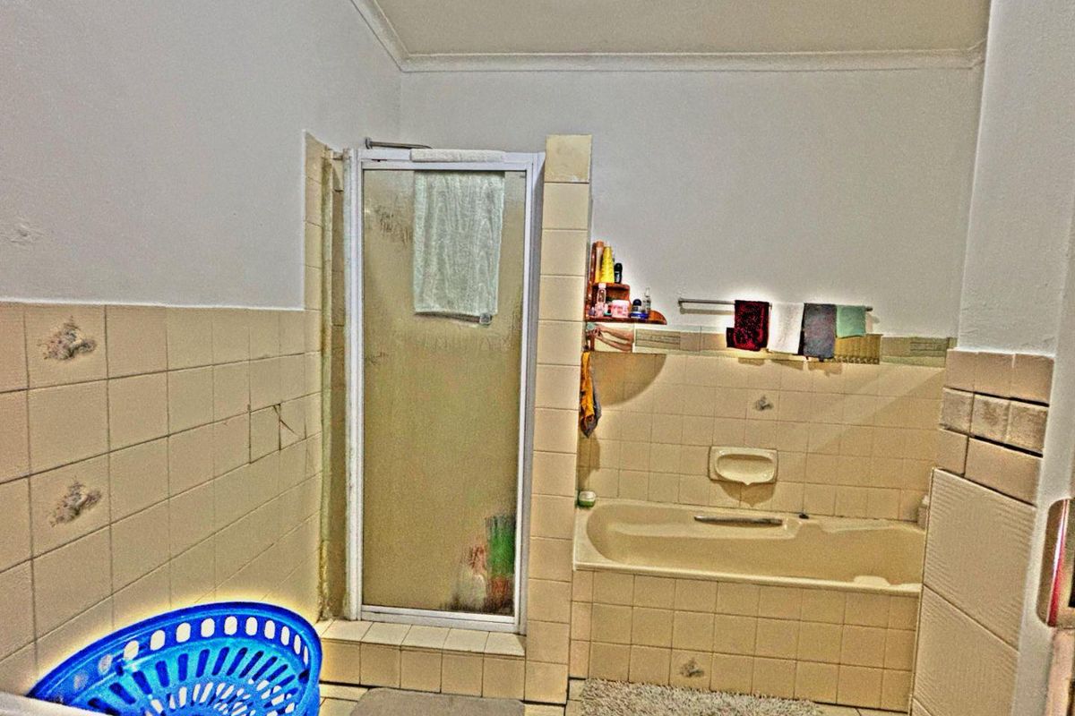 A dated bathroom featuring a built-in bathtub, a separate shower enclosure with tiled surround, and ceramic floor tiling.