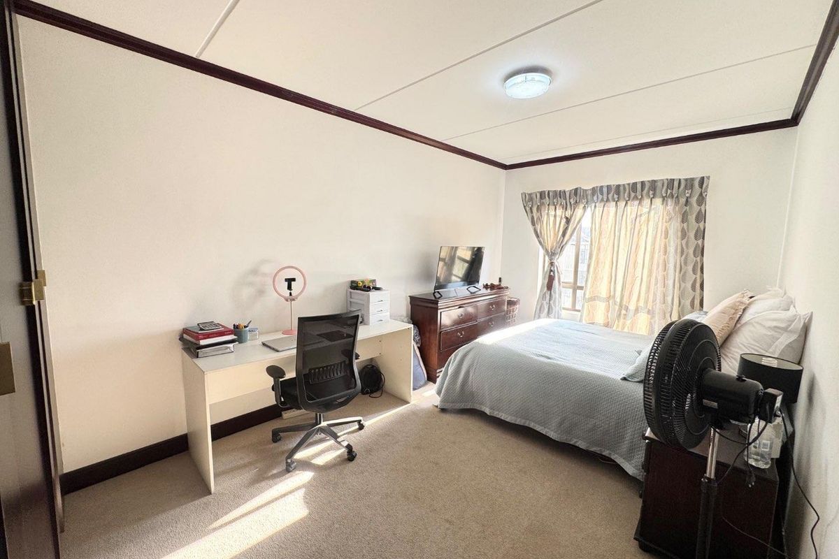A functional bedroom featuring neutral carpet flooring, a ceiling light fixture, and a window with curtain tracks, providing a comfortable living space.