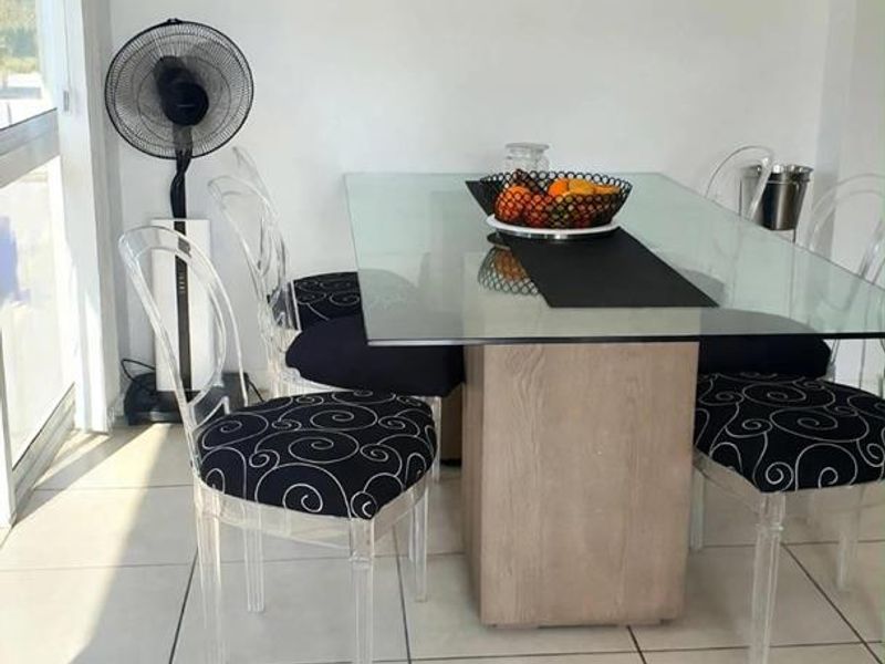 A bright dining area featuring neutral tiled flooring and a large sliding glass door providing natural light.