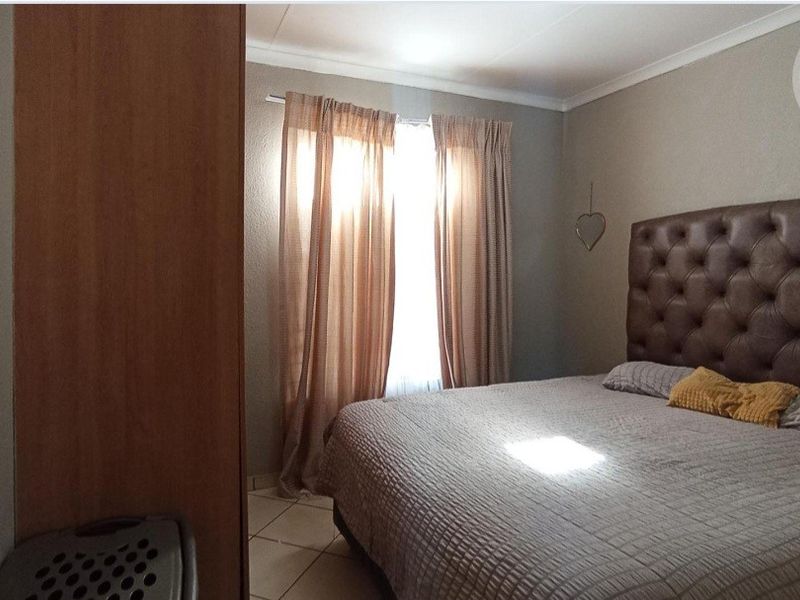 A functional bedroom featuring tiled flooring and neutral wall finishes, providing a comfortable and well-maintained sleeping space.