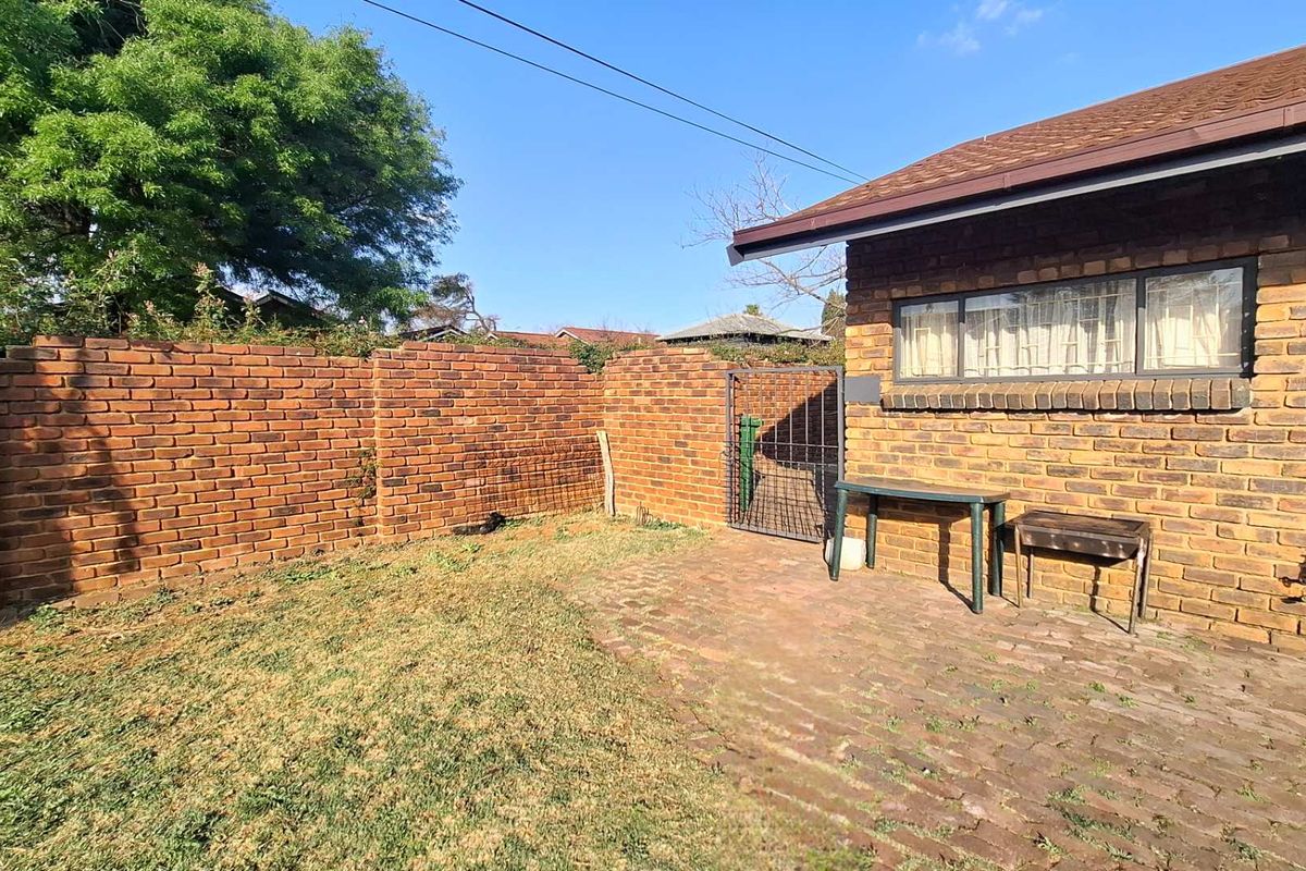 A private rear garden area featuring a brick boundary wall, paved patio space, and direct access to the main house structure.