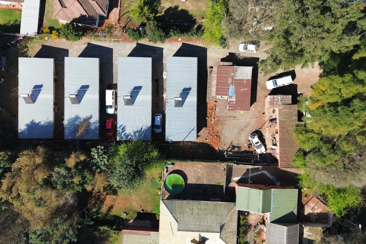 Aerial view of the property complex featuring multiple buildings with metal roofing, solar water heaters, and an outdoor swimming pool.