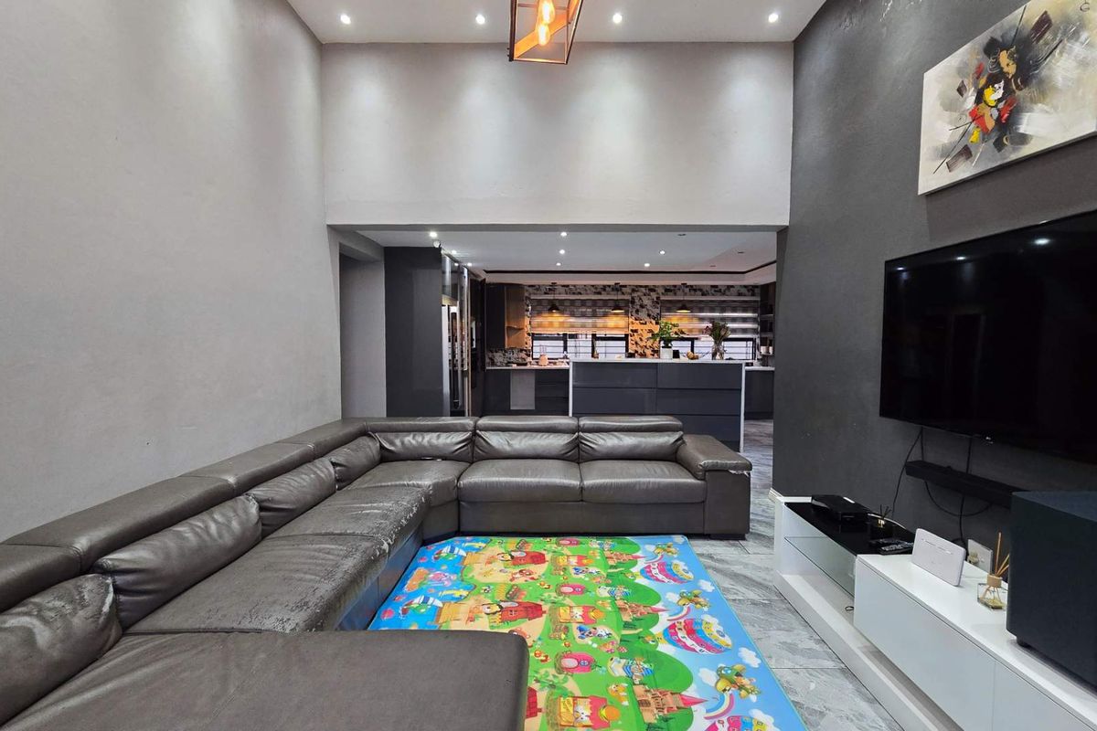 Spacious open-plan living area featuring high ceilings, modern recessed lighting, and tiled flooring, seamlessly flowing into the kitchen space.