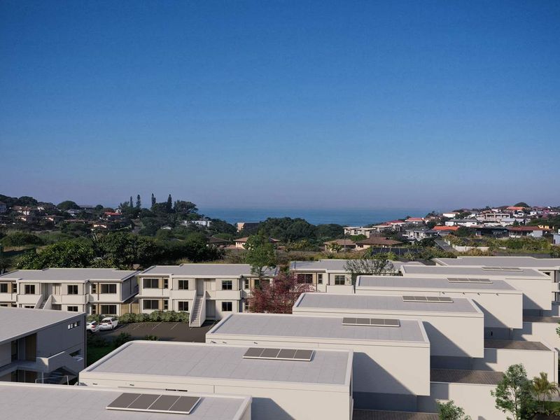 Aerial view of a modern townhouse complex featuring flat roofs with integrated solar panels and surrounding coastal landscape.