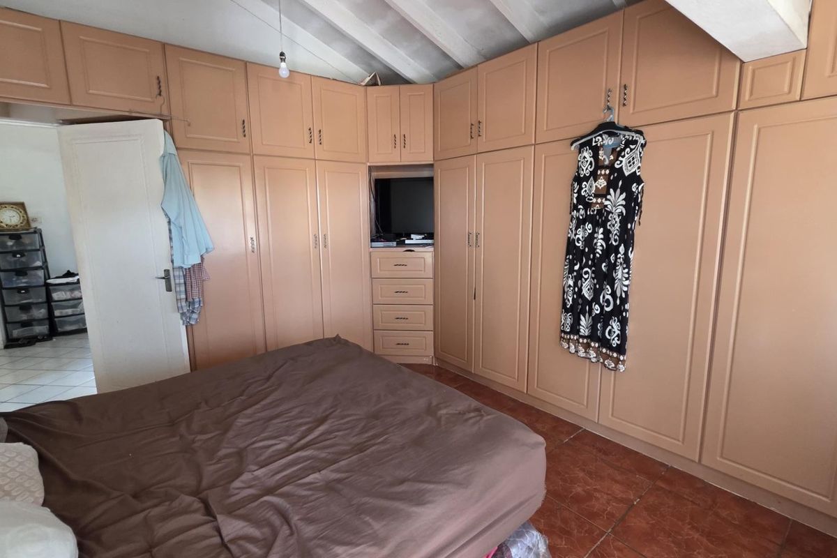 Bedroom featuring extensive built-in cabinetry, tiled flooring, and an exposed beam ceiling, offering ample storage space.