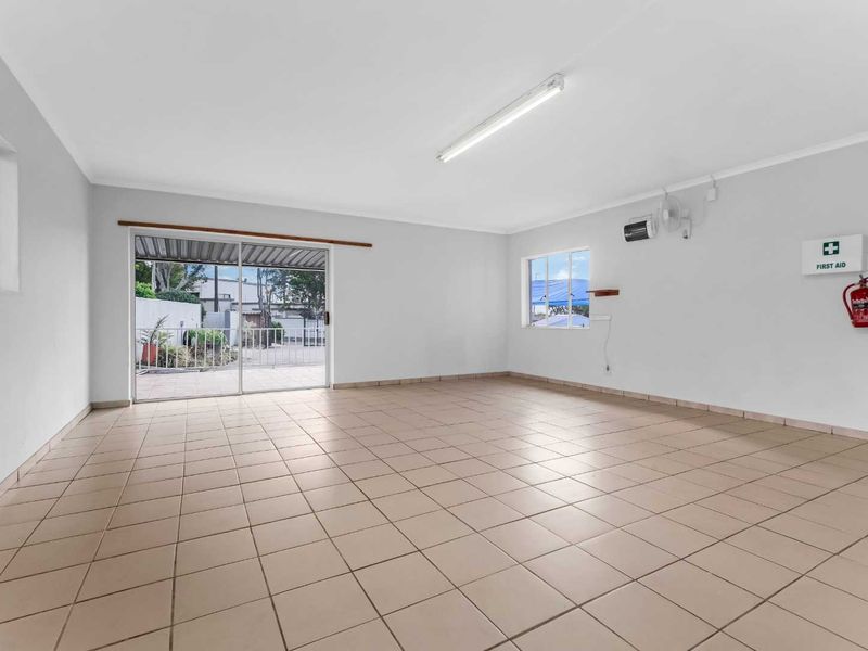 A spacious, empty living area featuring neutral tiled flooring, a sliding glass door leading to the exterior, and basic utility fixtures.