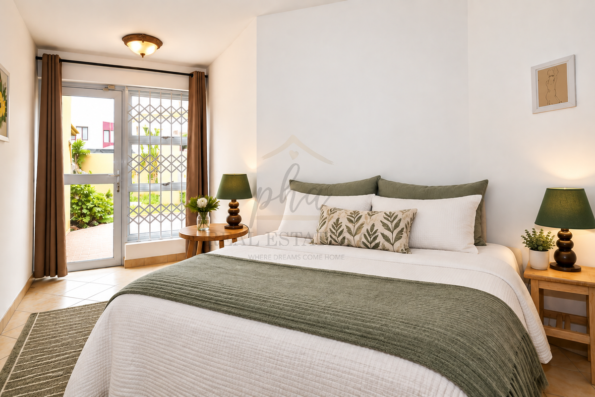 A well-lit bedroom featuring tiled flooring and a glass door with a security gate leading to an outdoor area.