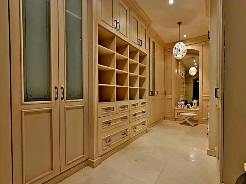 A spacious walk-in dressing room featuring extensive custom built-in cabinetry, integrated shelving, drawers, and elegant recessed lighting.