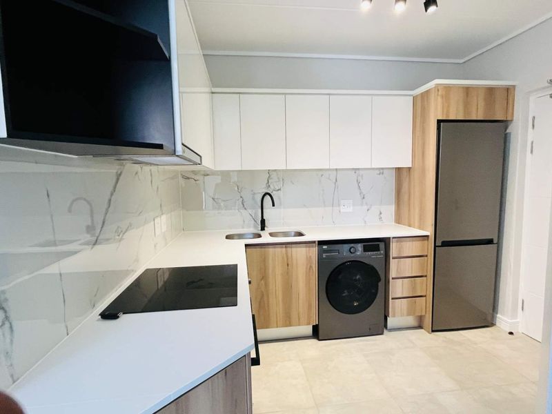 Modern kitchen featuring sleek white and wood-grain cabinetry, marble-look splashback, integrated appliances, and high-quality finishes throughout.