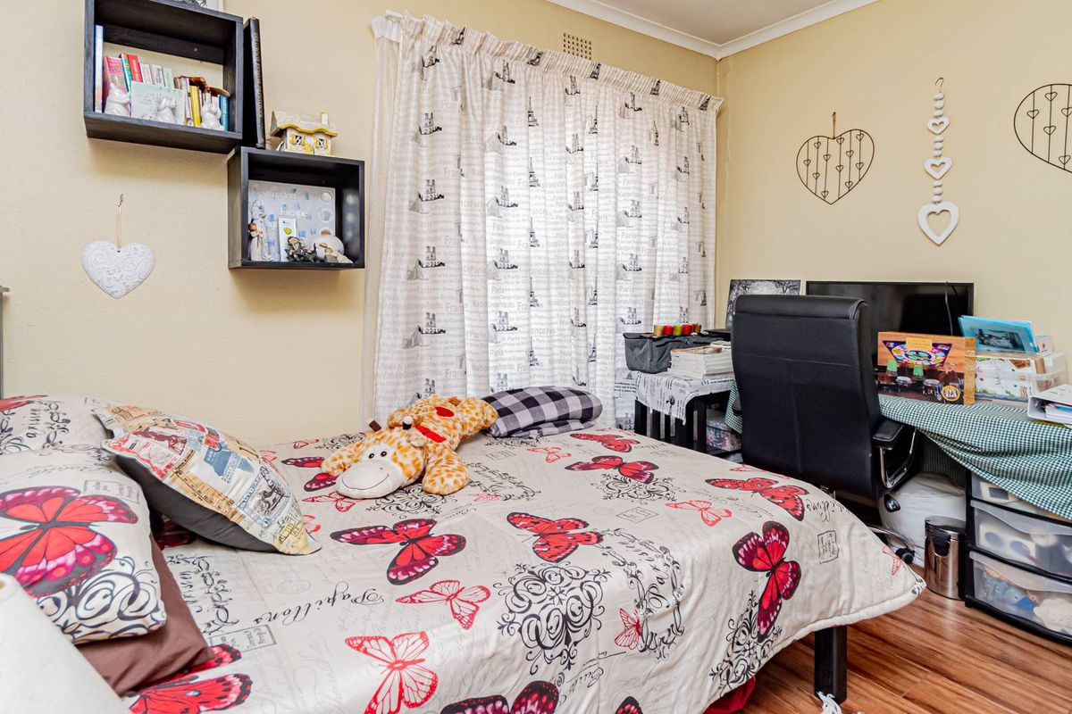 A bedroom featuring laminate flooring and a window with curtain tracks.