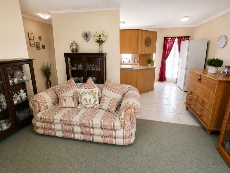 Open plan living and kitchen area featuring a combination of carpeted and tiled flooring with traditional timber kitchen cabinetry.