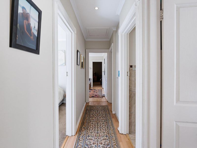 A well-maintained hallway featuring clean white trim, recessed lighting, and access to multiple rooms throughout the home.