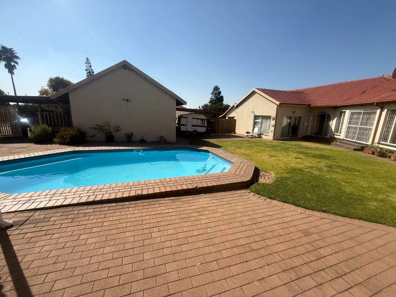 Spacious backyard featuring a swimming pool, paved patio area, and well-maintained lawn, providing an ideal space for outdoor relaxation and entertainment.