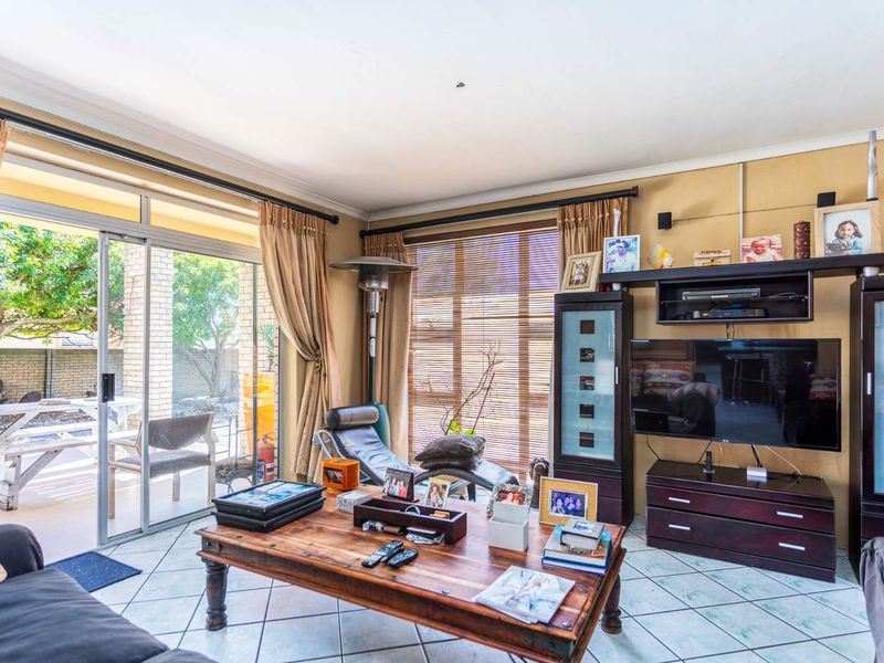 A comfortable living room featuring ceramic tile flooring, coved ceilings, and large sliding glass doors that provide direct access to the outdoor patio area.