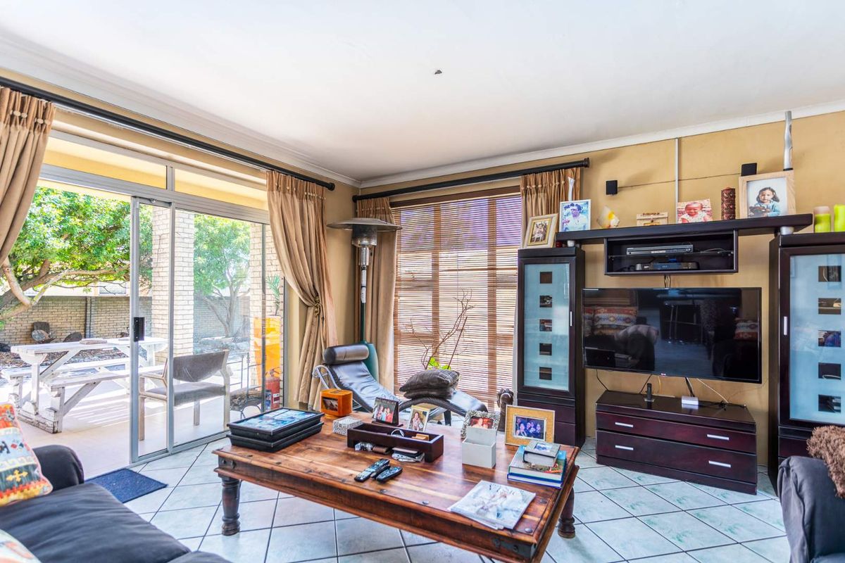 A comfortable living room featuring ceramic tile flooring, coved ceilings, and large sliding glass doors that provide direct access to the outdoor patio area.