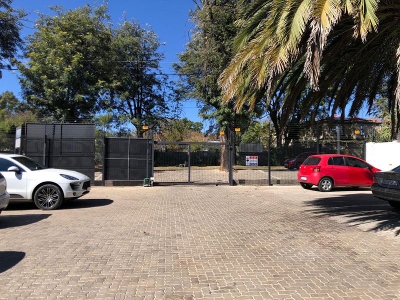 A paved office parking area featuring secure perimeter fencing and an automated entrance gate.
