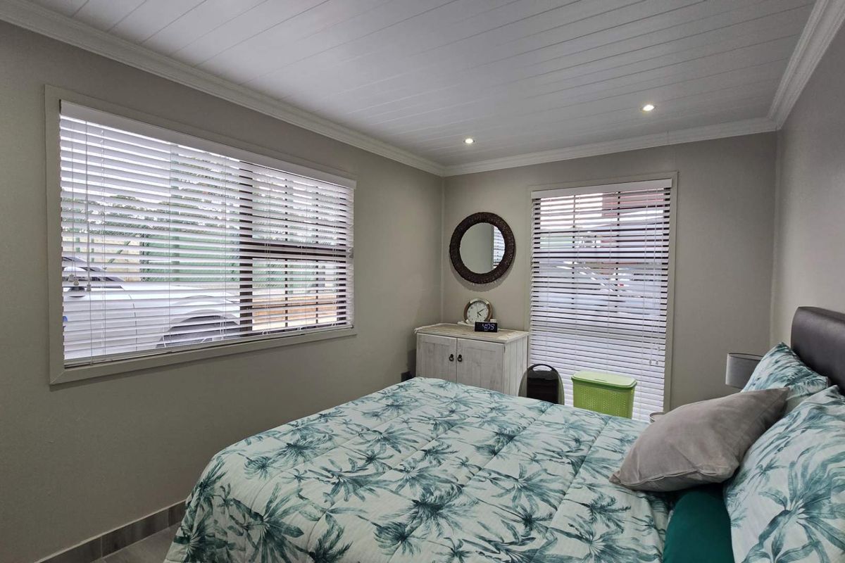 A well-maintained bedroom featuring neutral wall tones, recessed ceiling lighting, and horizontal window blinds.