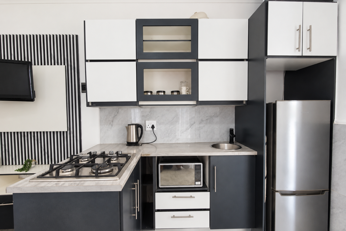 Modern compact kitchen featuring two-tone cabinetry, marble-look splashback, gas hob, and integrated microwave, offering a sleek and functional culinary space.