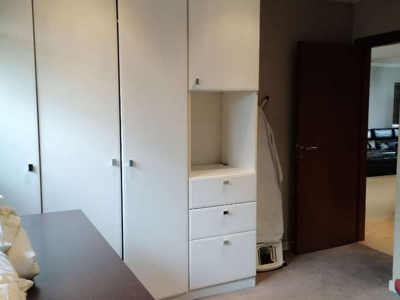 A bedroom featuring built-in white cabinetry with integrated drawers and recessed ceiling lighting, finished with neutral carpeting.