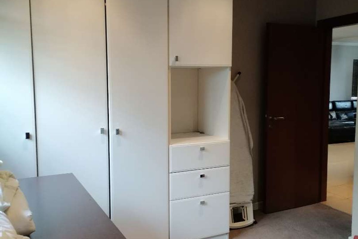 A bedroom featuring built-in white cabinetry with integrated drawers and recessed ceiling lighting, finished with neutral carpeting.