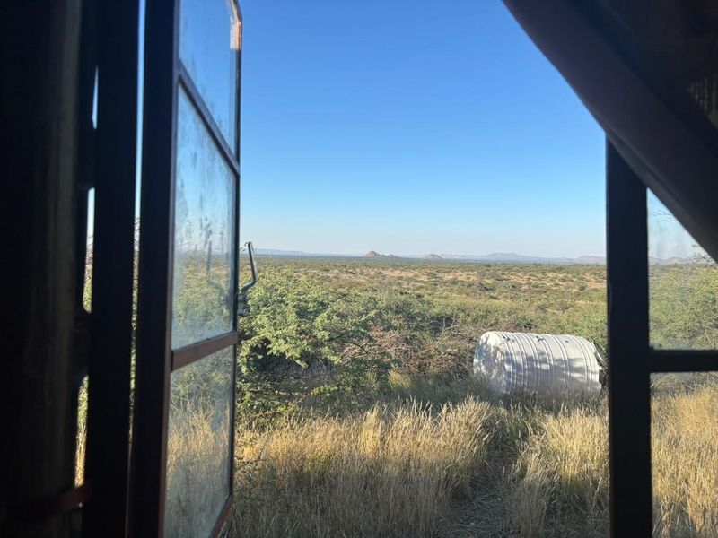 A view looking out from an interior window across the natural landscape, featuring a water storage tank in the distance.