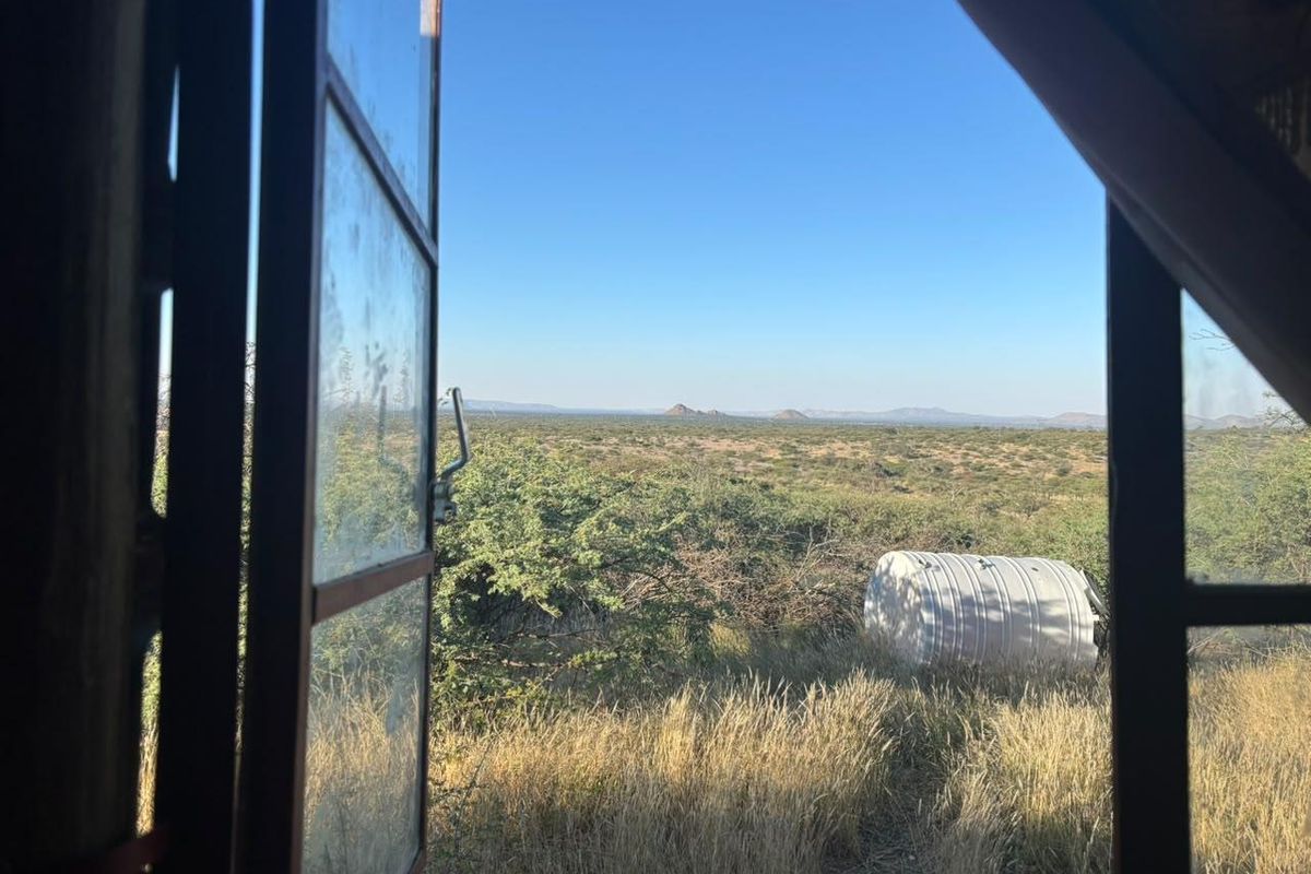 A view looking out from an interior window across the natural landscape, featuring a water storage tank in the distance.