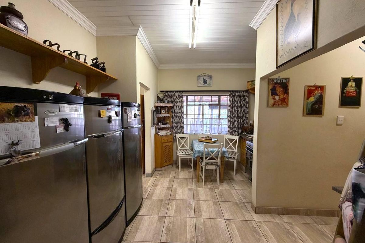 A functional kitchen area featuring tiled flooring, timber ceiling detailing, and built-in shelving, offering a practical layout for daily use.