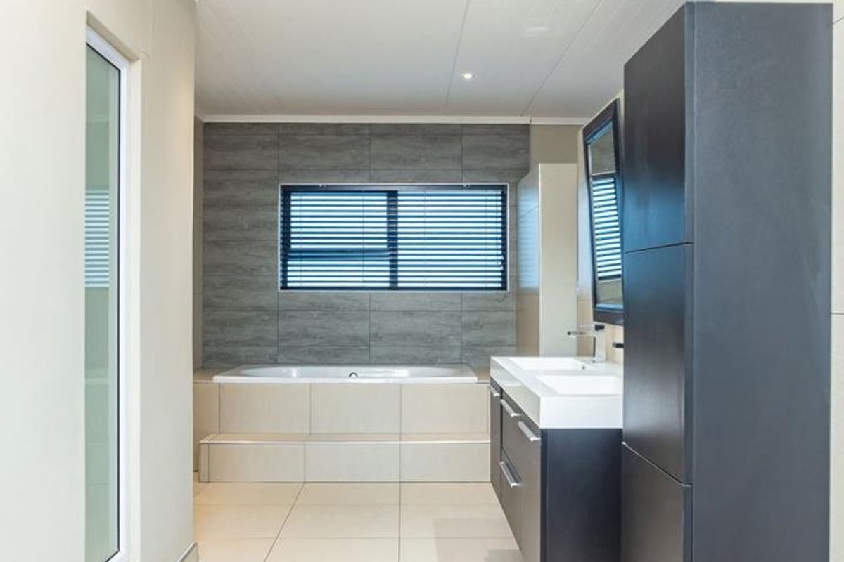 Modern bathroom featuring a built-in bathtub, dual vanity with dark cabinetry, and large format floor tiles.