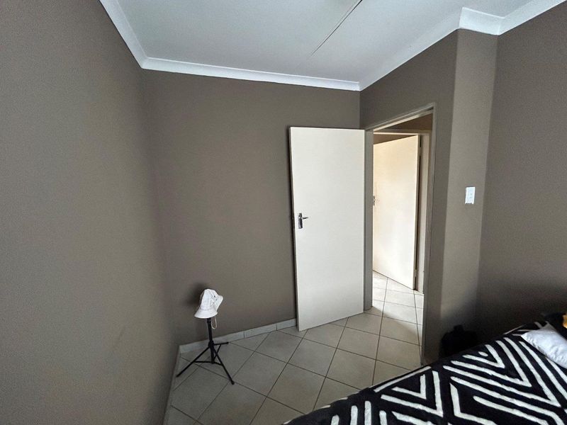 A neutral-toned bedroom featuring tiled flooring and white door frames, offering a clean and versatile space ready for personalization.