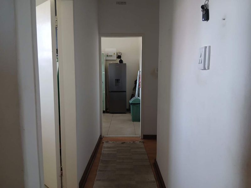 A functional hallway connecting to an adjacent utility or kitchen area, featuring neutral walls and standard flooring.