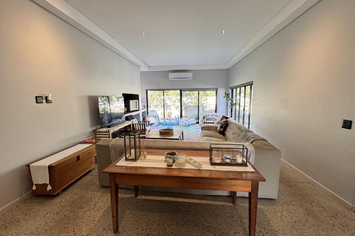 Spacious living room featuring modern terrazzo flooring, recessed downlighting, and large sliding glass doors that provide ample natural light and access to the outdoors.