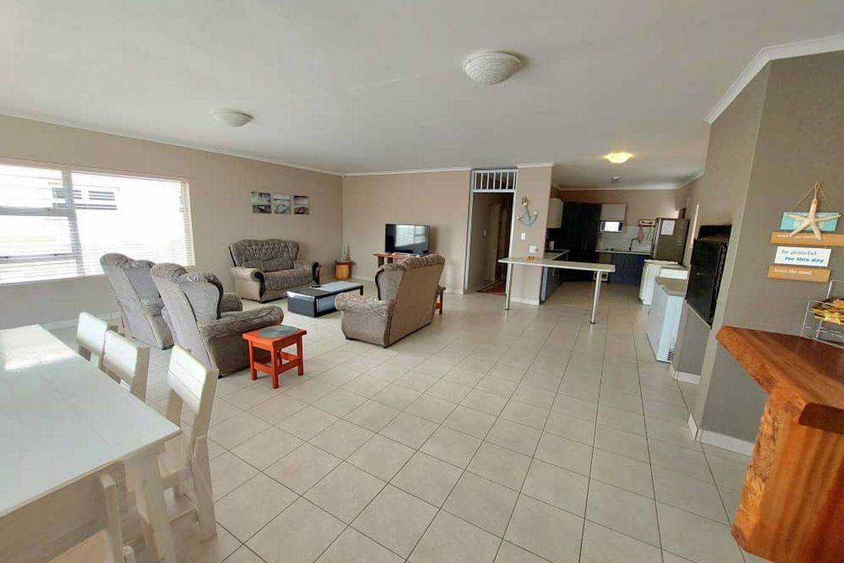 Spacious open-plan living and dining area featuring tiled flooring, integrated kitchen space, and neutral wall finishes, offering a versatile layout for family living.