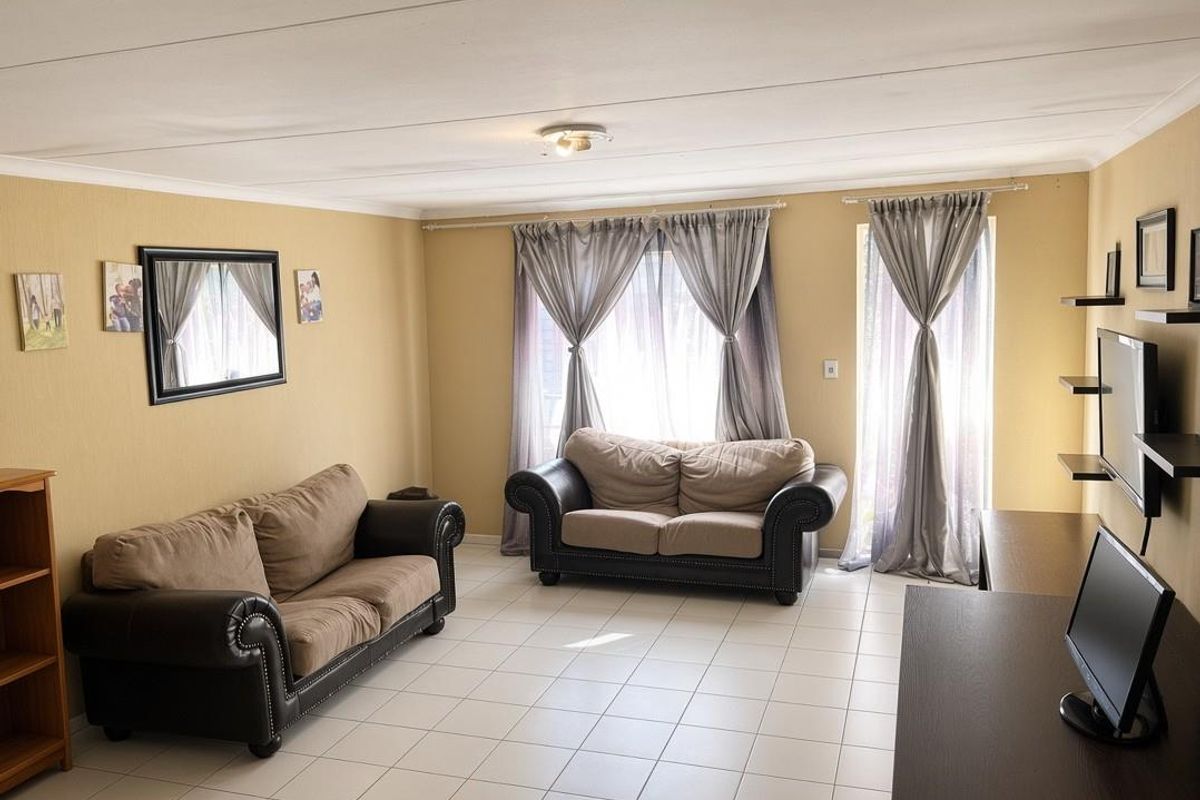 A spacious living room featuring neutral tiled flooring, soft yellow walls, and natural light through large windows with curtain fixtures.